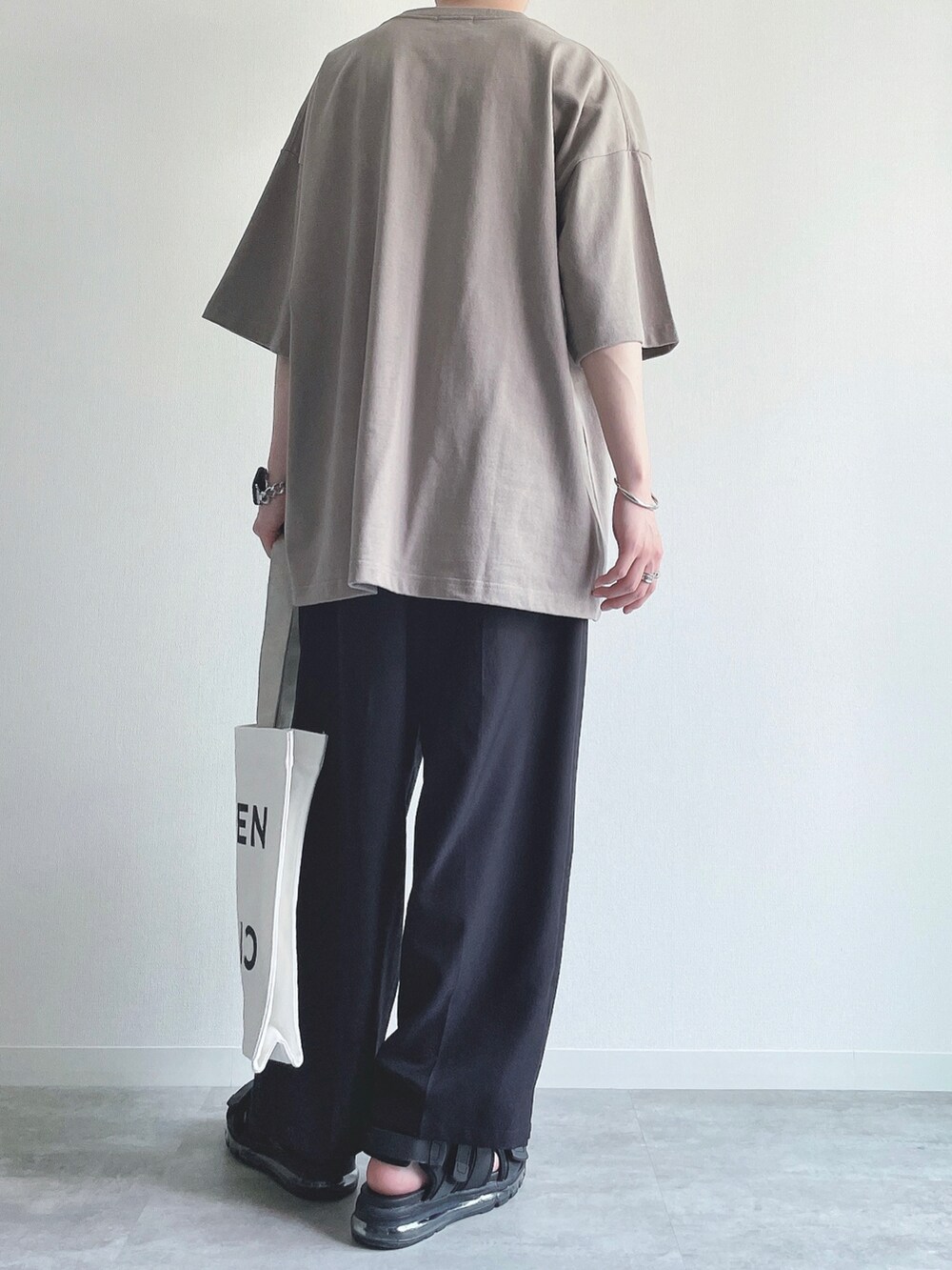 ベージュ系のTシャツ/カットソー、ブラック系のスラックス、ブラック系のサンダルを着用したメンズの夏コーディネートの4枚目の写真
