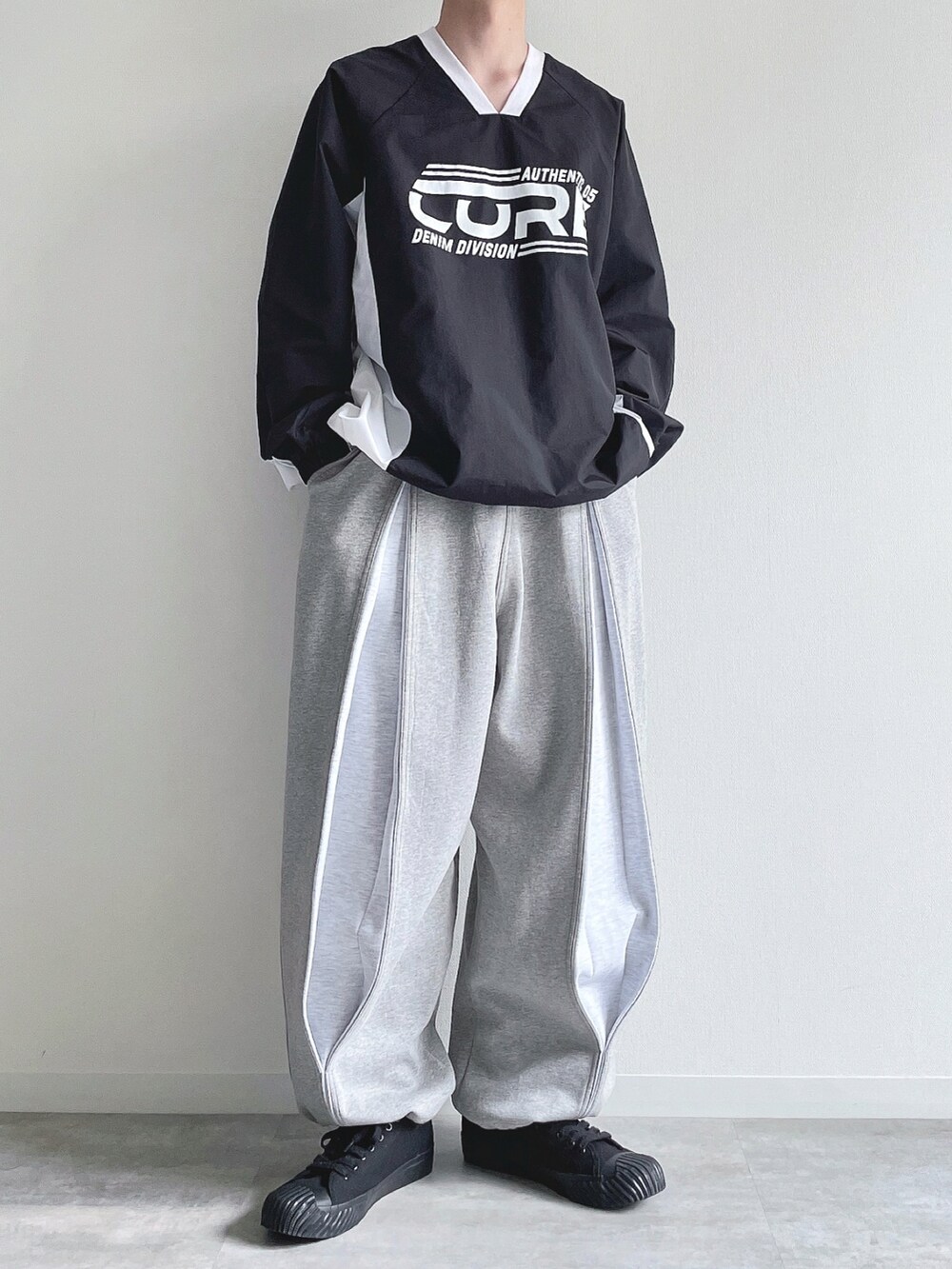 ブラック系のパーカー、グレー系のパンツ、ブラック系のスニーカーを着用したメンズの春コーディネートの5枚目の写真