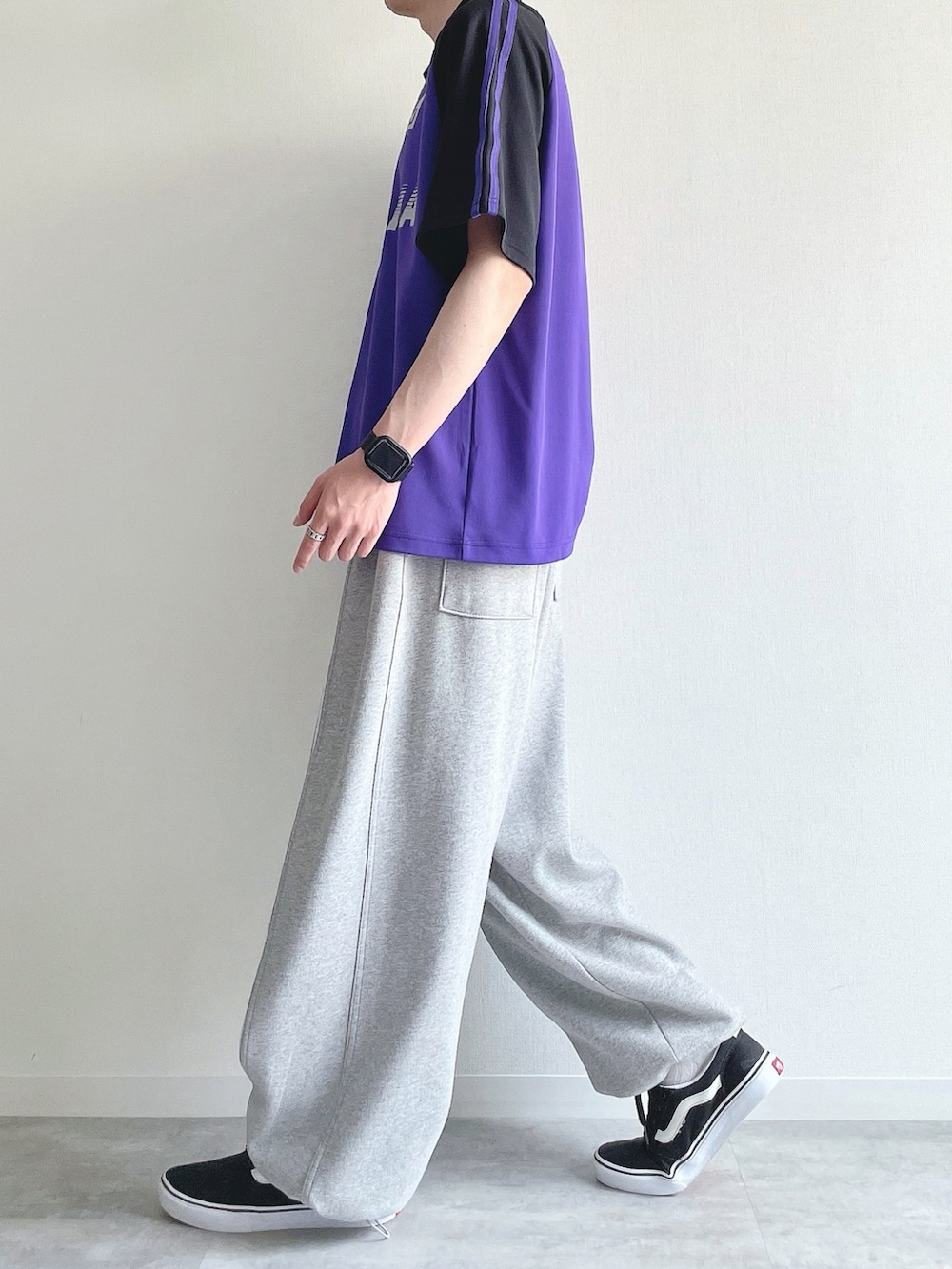 パープル系のTシャツ/カットソー、グレー系のパンツ、ブラック系のスニーカーを着用したメンズの秋コーディネートの3枚目の写真