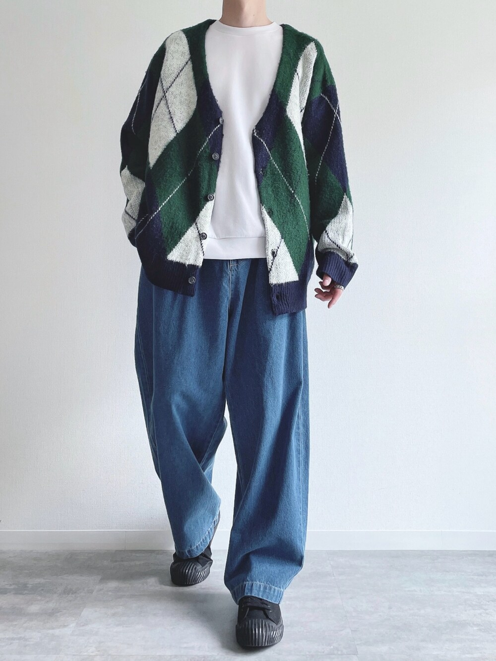 グリーン系のカーディガン/ボレロ、ホワイト系のトップス、ブルー系のデニムパンツを着用したメンズの秋コーディネートの2枚目の写真