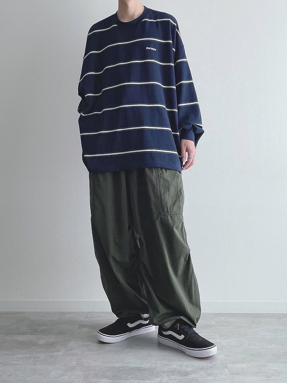 ブルー系のTシャツ/カットソー、グリーン系のカーゴパンツ、ブラック系のスニーカーを着用したメンズの秋コーディネートの2枚目の写真