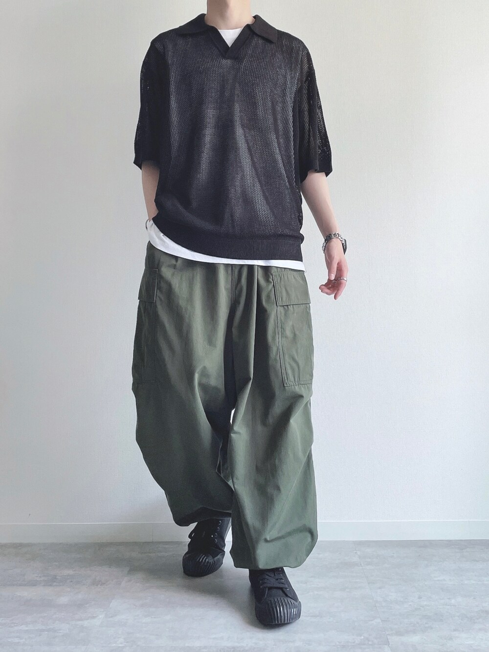 ブラック系のトップス、ホワイト系のタンクトップ、グリーン系のカーゴパンツを着用したメンズの夏コーディネートの2枚目の写真
