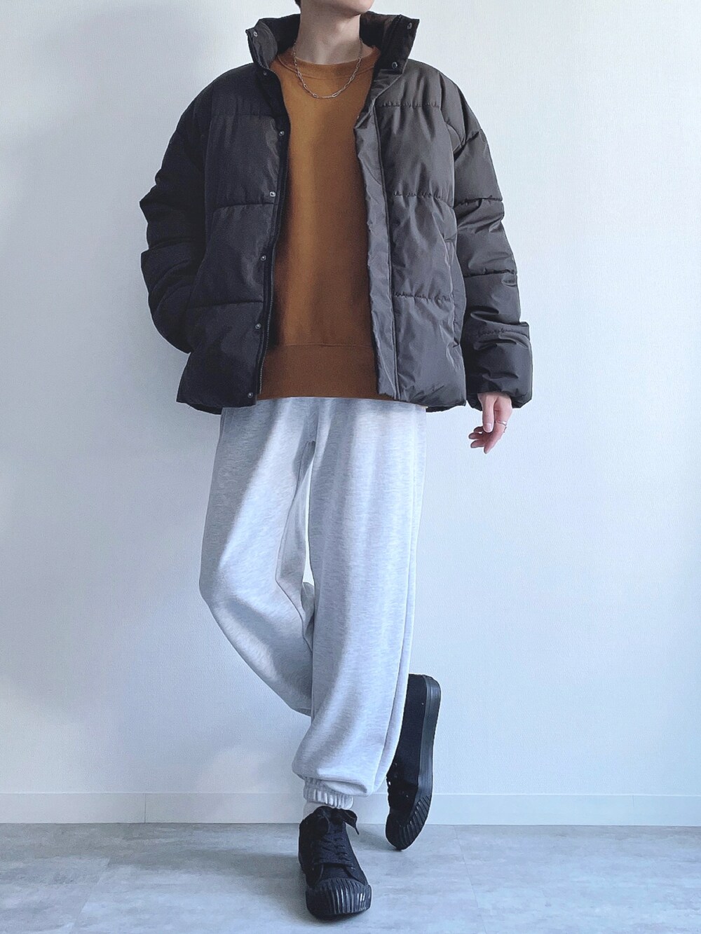 ブラック系のダウンジャケット/コート、イエロー系のトップス、グレー系のスウェットパンツを着用したメンズの冬コーディネートの4枚目の写真