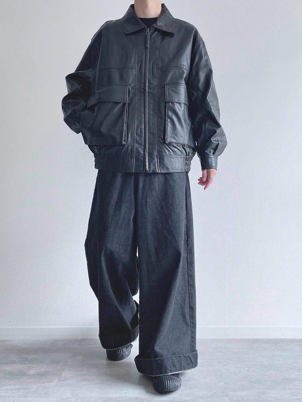 ブラック系のブルゾン、ブラック系のTシャツ/カットソー、ブラック系のデニムパンツを着用したメンズの冬コーディネートの2枚目の写真