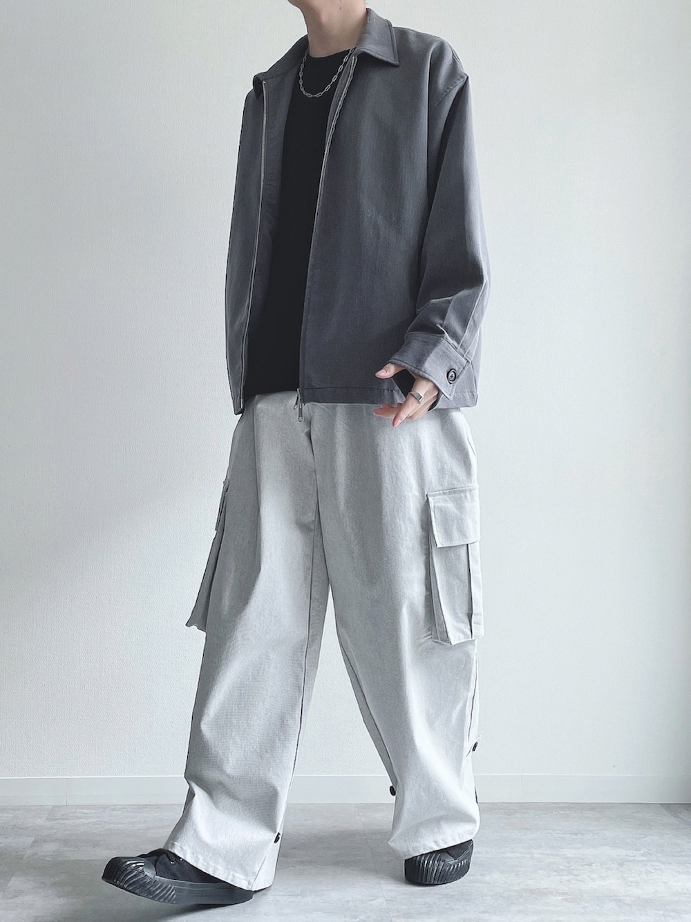 グレー系のブルゾン、ブラック系のトップス、ホワイト系のカーゴパンツを着用したメンズの春コーディネートの5枚目の写真