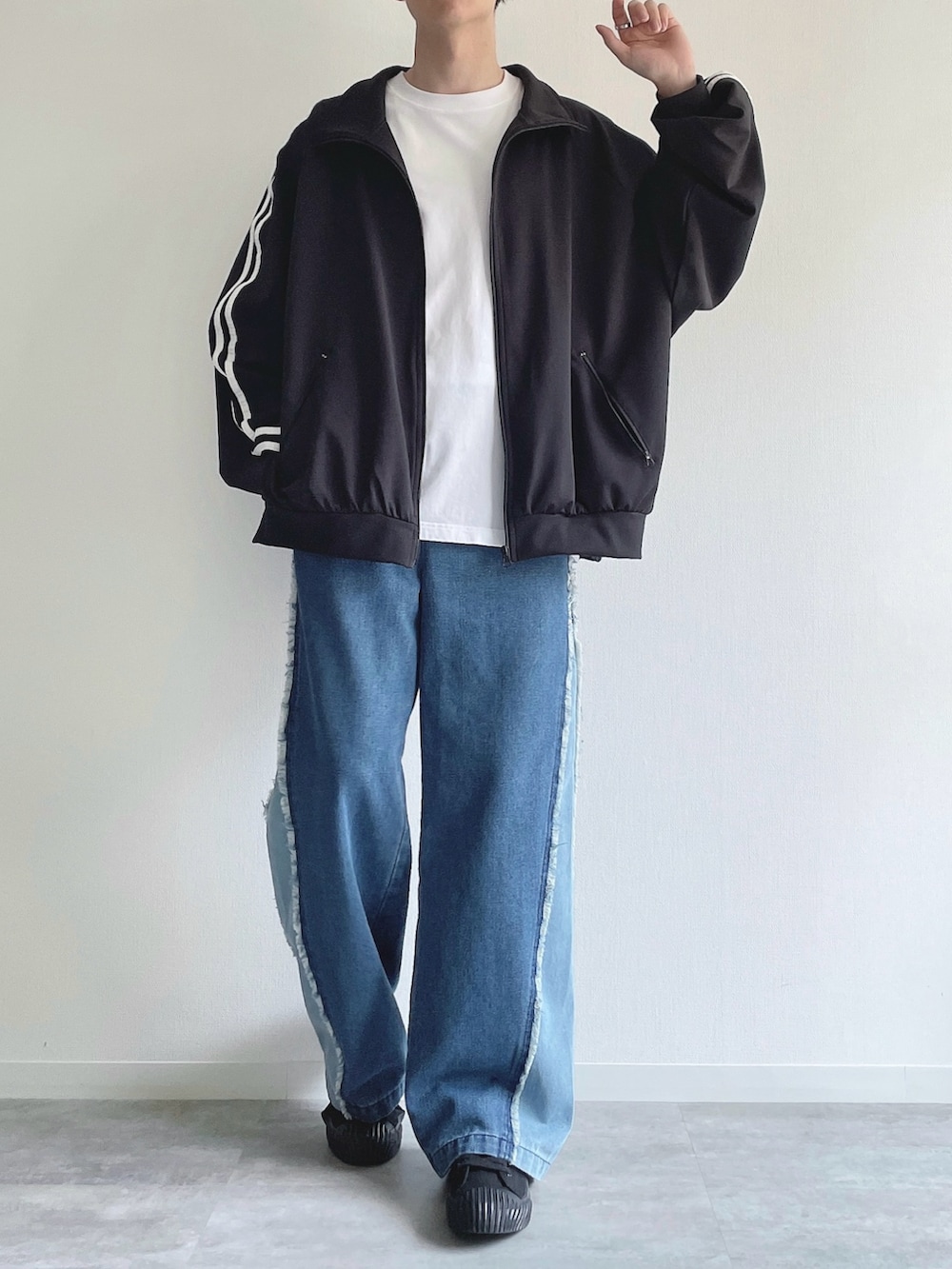 ブラック系のブルゾン、ホワイト系のTシャツ/カットソー、ブルー系のデニムパンツを着用したメンズの秋コーディネートの2枚目の写真