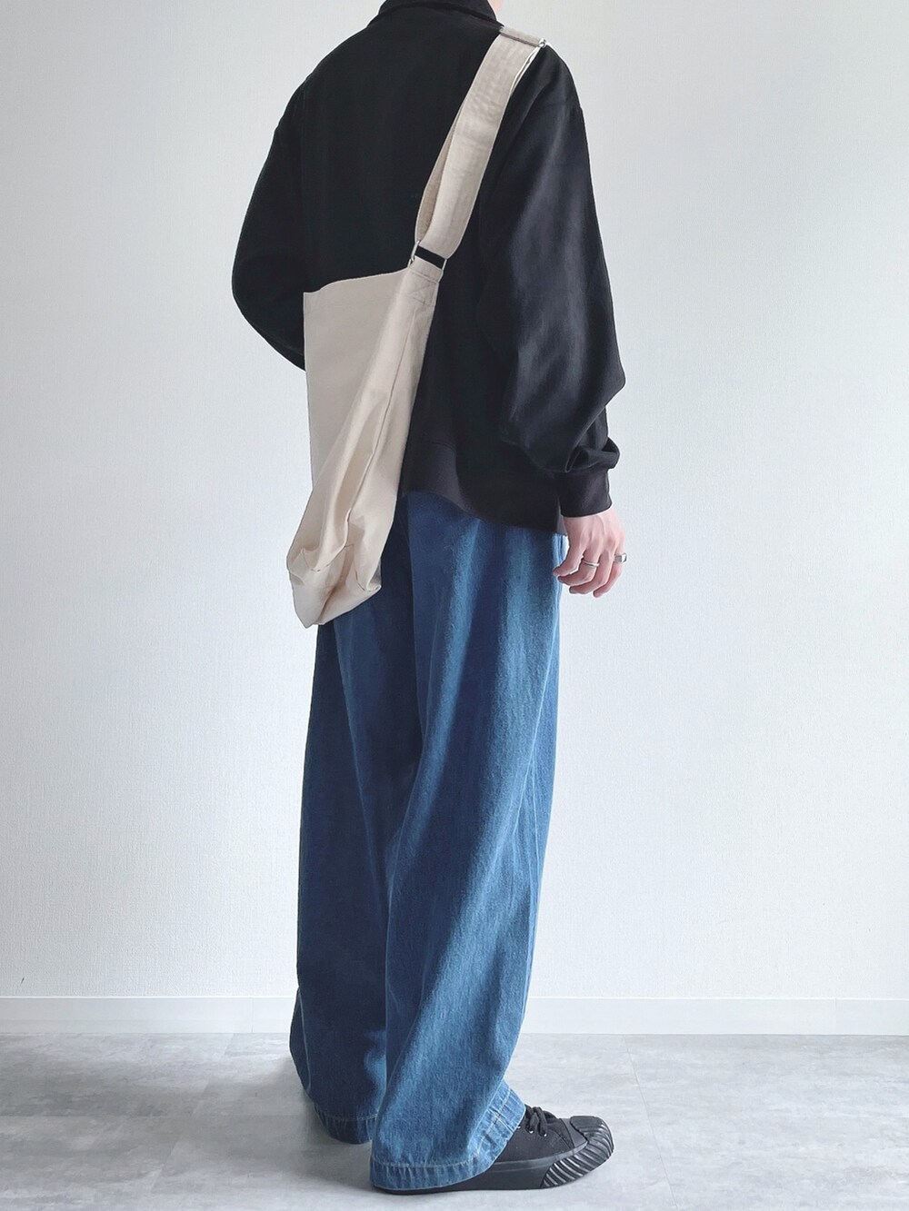 ブラック系のスウェット、ブルー系のデニムパンツ、ブラック系のスニーカーを着用したメンズの秋コーディネートの4枚目の写真