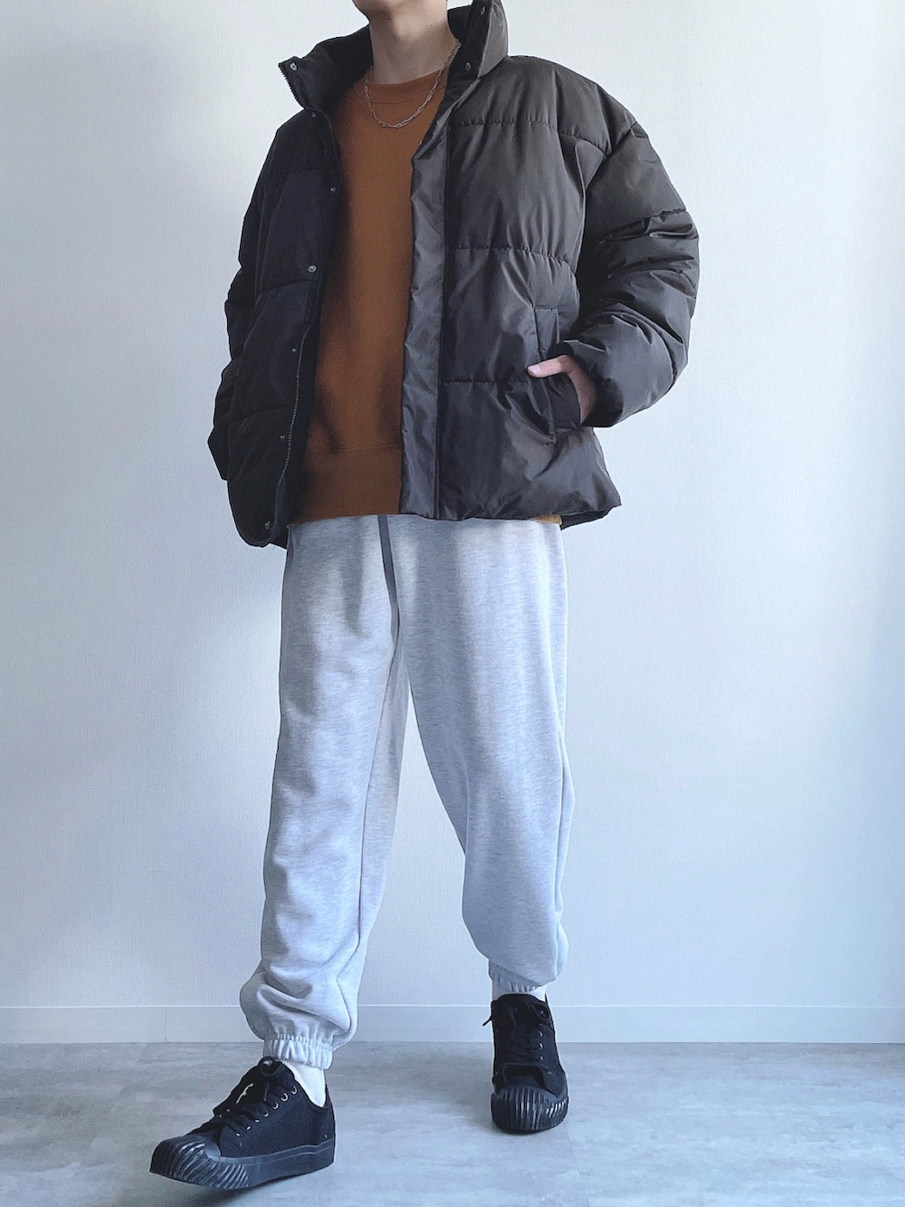 ブラック系のダウンジャケット/コート、イエロー系のトップス、グレー系のスウェットパンツを着用したメンズの冬コーディネートの5枚目の写真