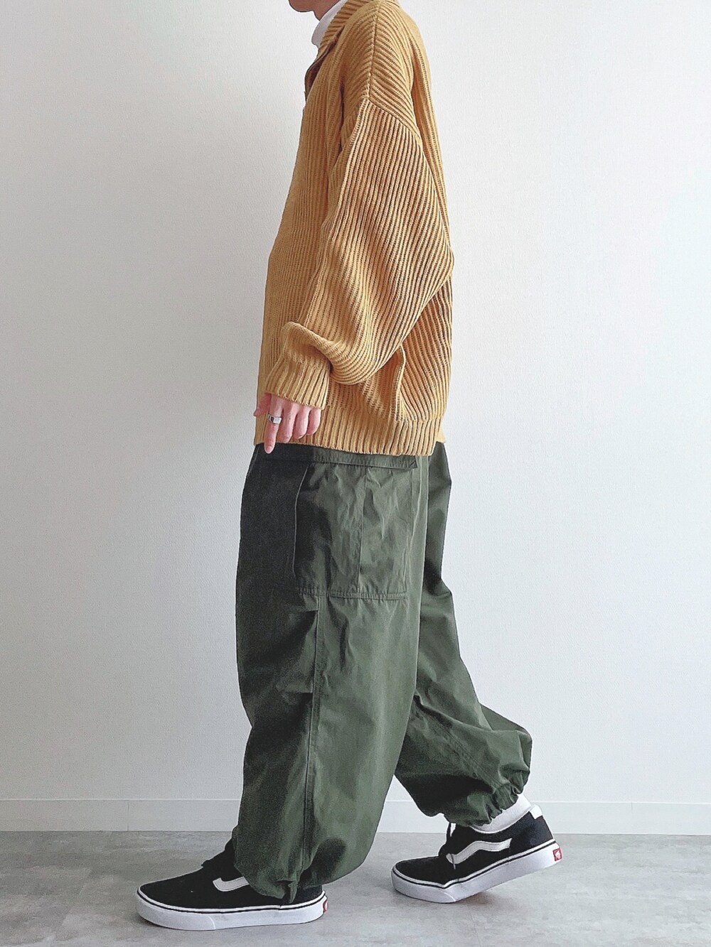 イエロー系のニット/セーター、ホワイト系のTシャツ/カットソー、グリーン系のカーゴパンツを着用したメンズの冬コーディネートの2枚目の写真