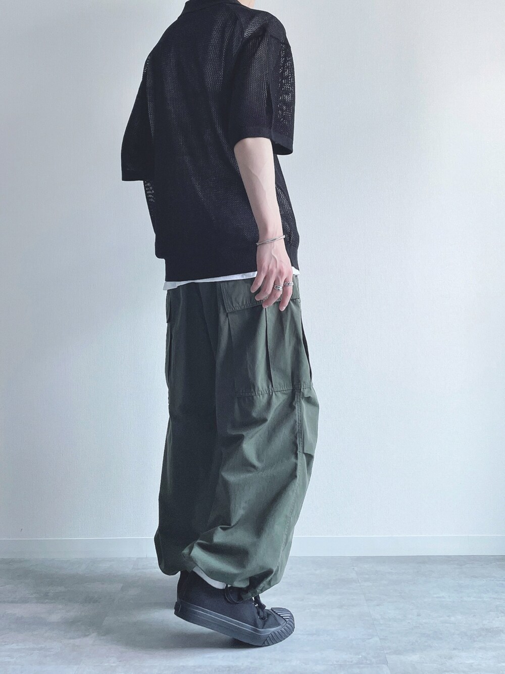 ブラック系のトップス、ホワイト系のタンクトップ、グリーン系のカーゴパンツを着用したメンズの夏コーディネートの4枚目の写真