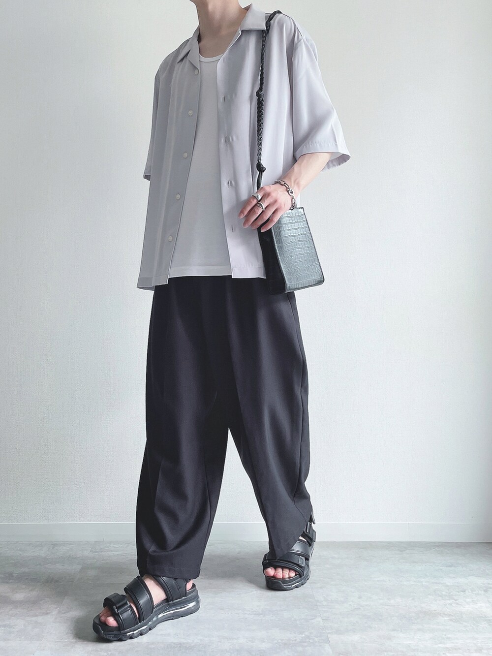 グレー系のトップス、ホワイト系のタンクトップ、ブラック系のスラックスを着用したメンズの夏コーディネートの5枚目の写真