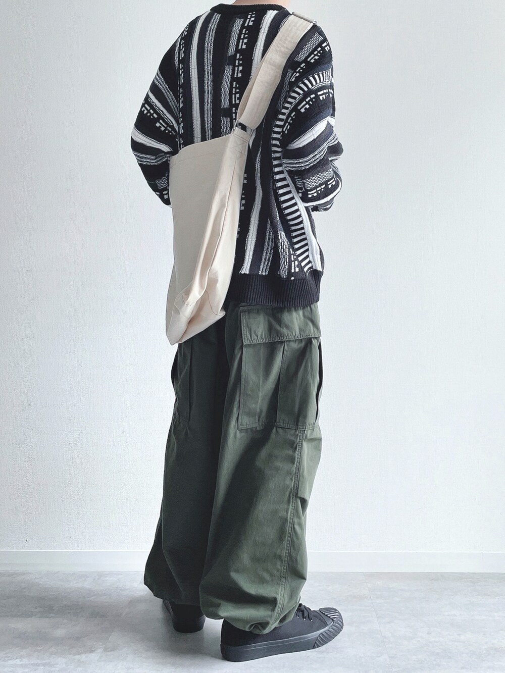 ブラック系のニット/セーター、グリーン系のカーゴパンツ、ブラック系のスニーカーを着用したメンズの冬コーディネートの4枚目の写真