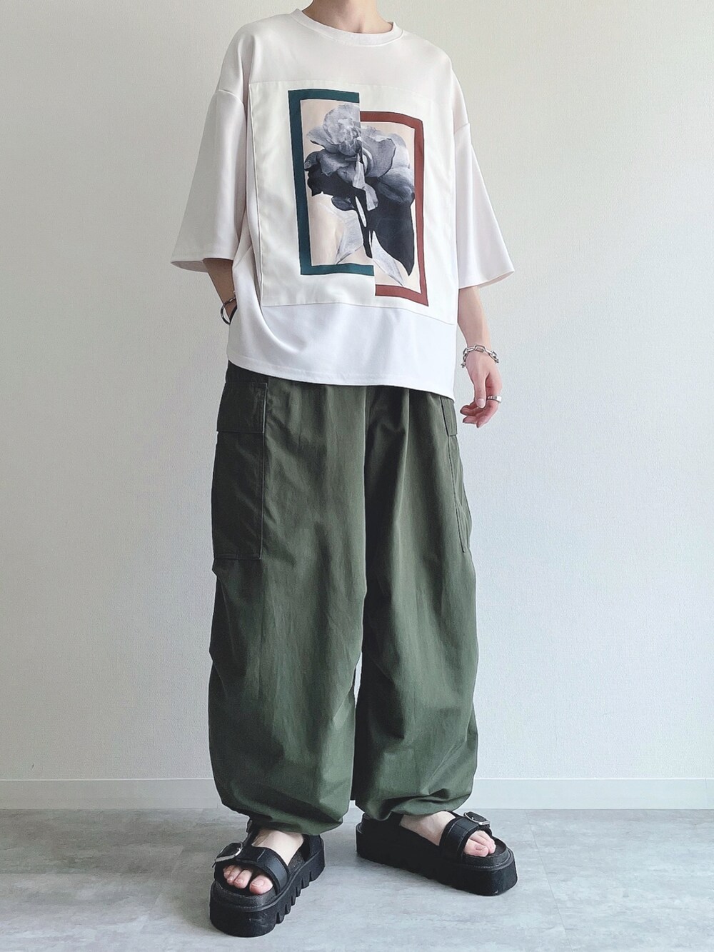 ホワイト系のTシャツ/カットソー、グリーン系のカーゴパンツ、ブラック系のサンダルを着用したメンズの夏コーディネートの2枚目の写真