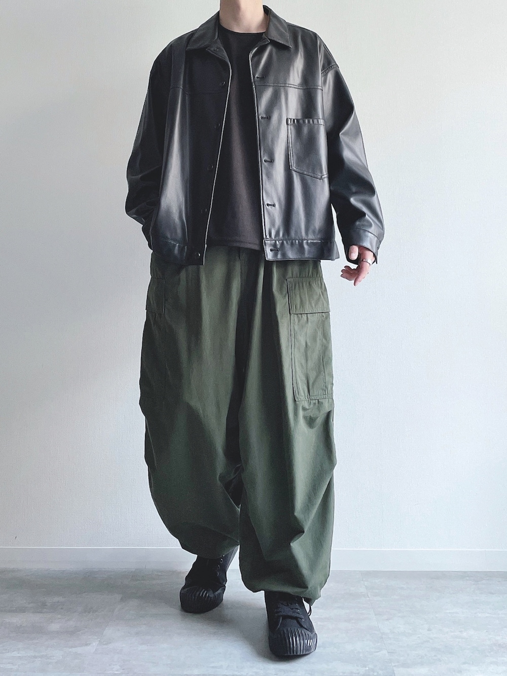 ブラック系のブルゾン、ブラック系のTシャツ/カットソー、グリーン系のカーゴパンツを着用したメンズの秋コーディネートの2枚目の写真