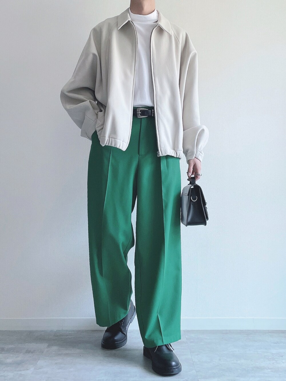 ホワイト系のブルゾン、ホワイト系のTシャツ/カットソー、グリーン系のスラックスを着用したメンズの春コーディネートの2枚目の写真