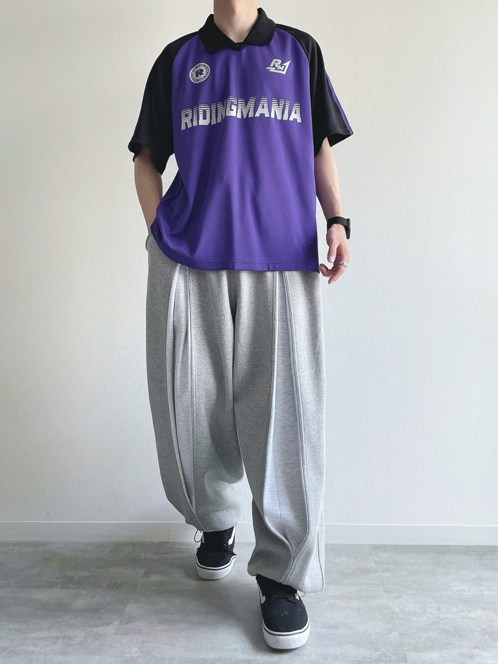 パープル系のTシャツ/カットソー、グレー系のパンツ、ブラック系のスニーカーを着用したメンズの秋コーディネートの2枚目の写真