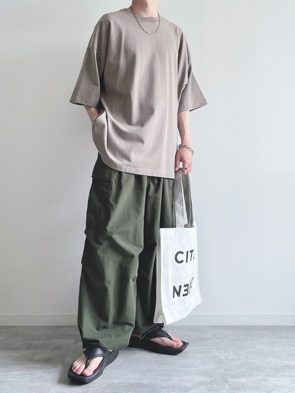 ベージュ系のTシャツ/カットソー、グリーン系のカーゴパンツ、ブラック系のサンダルを着用したメンズの夏コーディネートの5枚目の写真