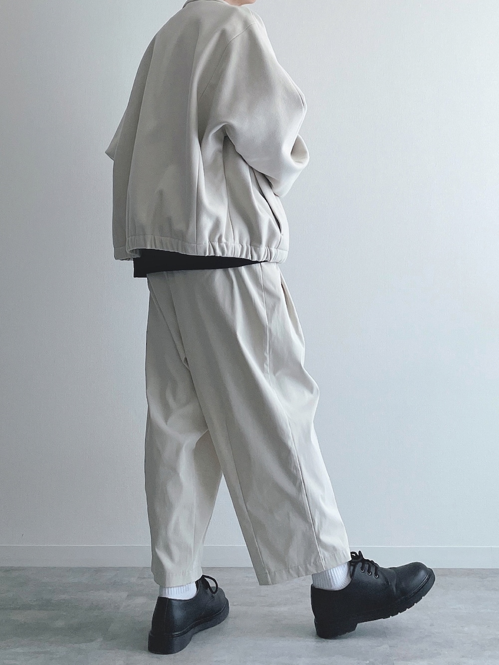 ホワイト系のブルゾン、ブラック系のトップス、ホワイト系のその他パンツを着用したメンズの秋コーディネートの2枚目の写真