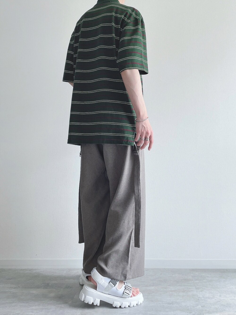 グリーン系のトップス、ベージュ系のスラックス、ホワイト系のサンダルを着用したメンズの夏コーディネートの4枚目の写真