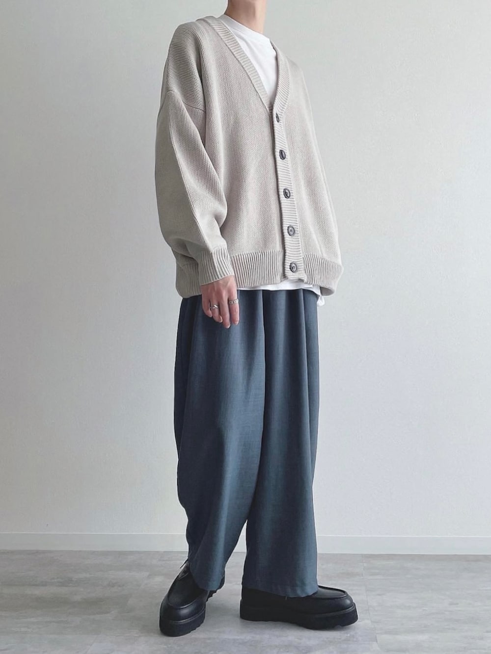 グレー系のカーディガン/ボレロ、ホワイト系のTシャツ/カットソー、ブルー系のスラックスを着用したメンズの秋コーディネートの2枚目の写真