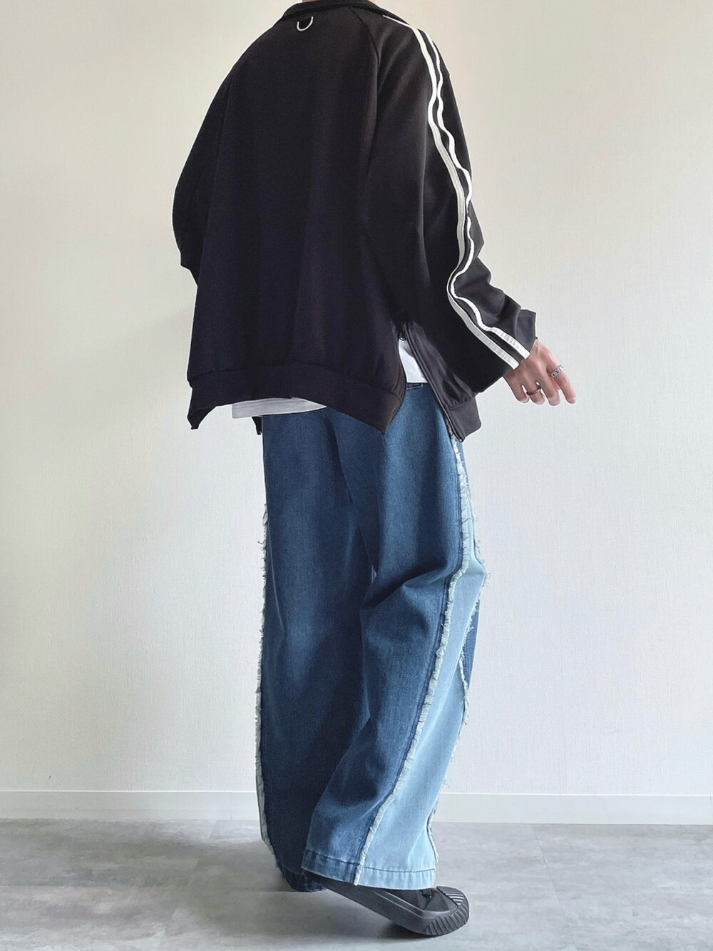 ブラック系のブルゾン、ホワイト系のTシャツ/カットソー、ブルー系のデニムパンツを着用したメンズの秋コーディネートの4枚目の写真