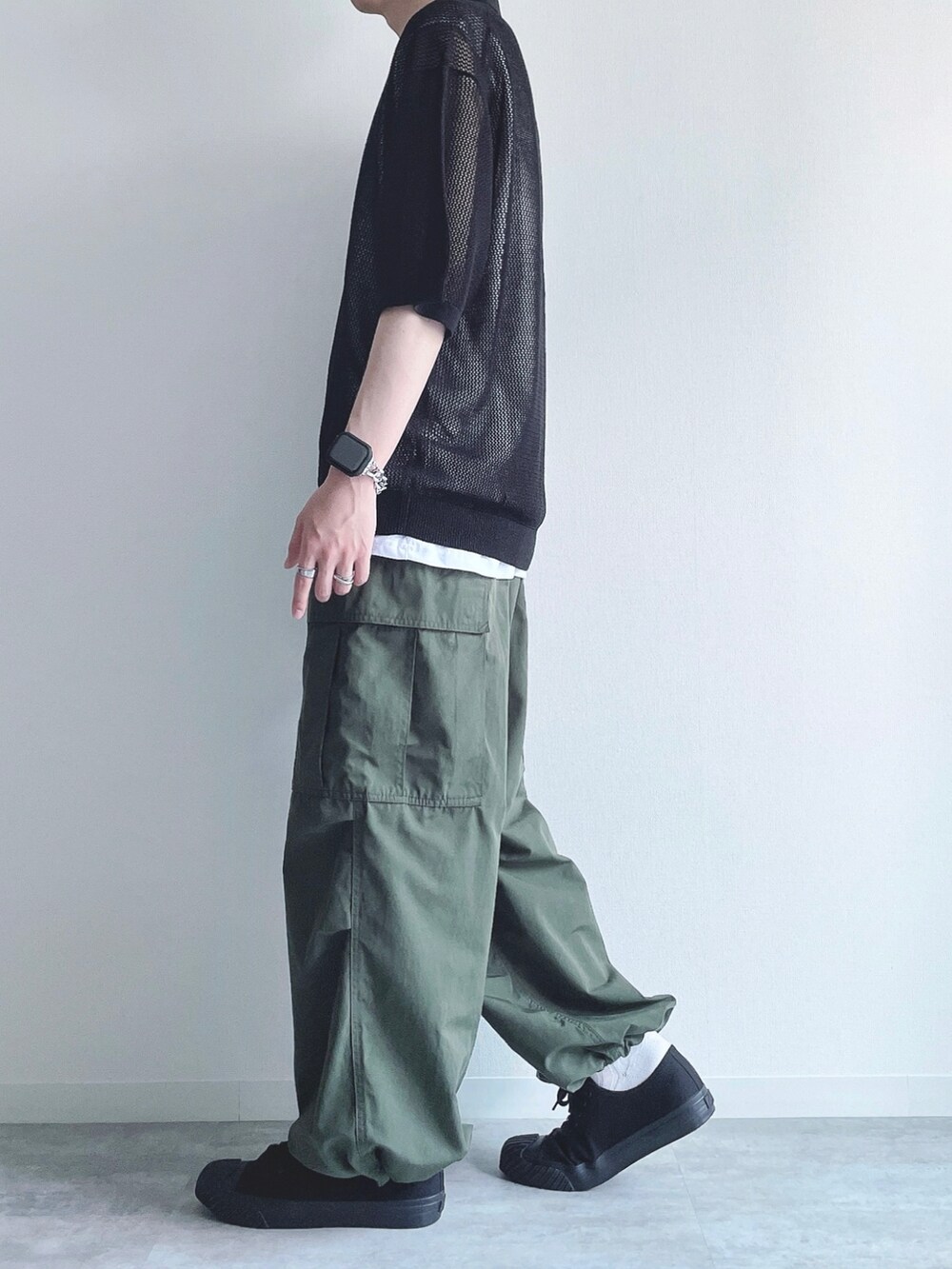 ブラック系のトップス、ホワイト系のタンクトップ、グリーン系のカーゴパンツを着用したメンズの夏コーディネートの3枚目の写真