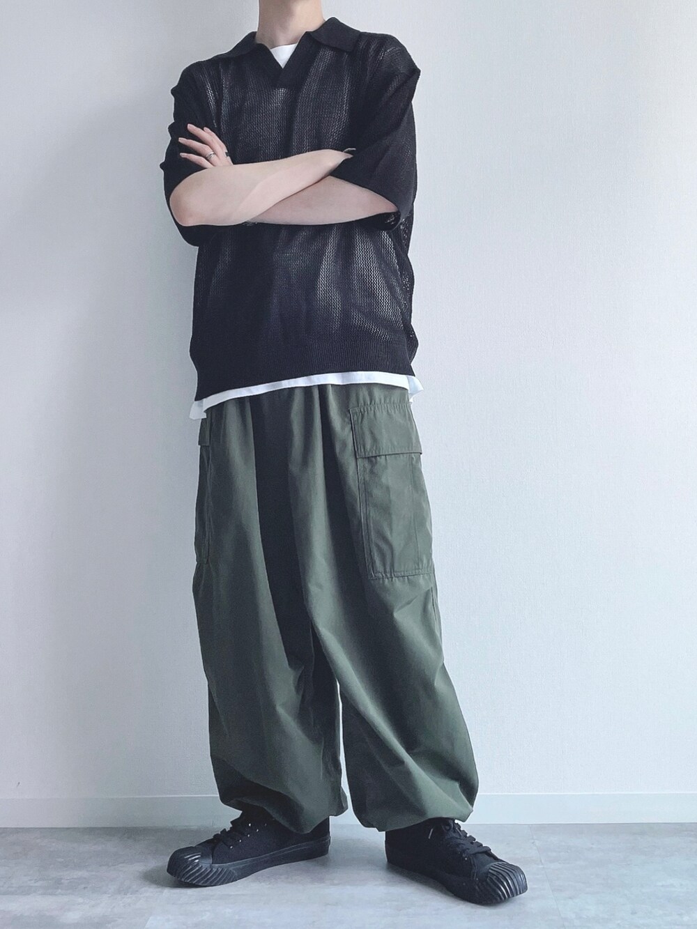 ブラック系のトップス、ホワイト系のタンクトップ、グリーン系のカーゴパンツを着用したメンズの夏コーディネートの5枚目の写真
