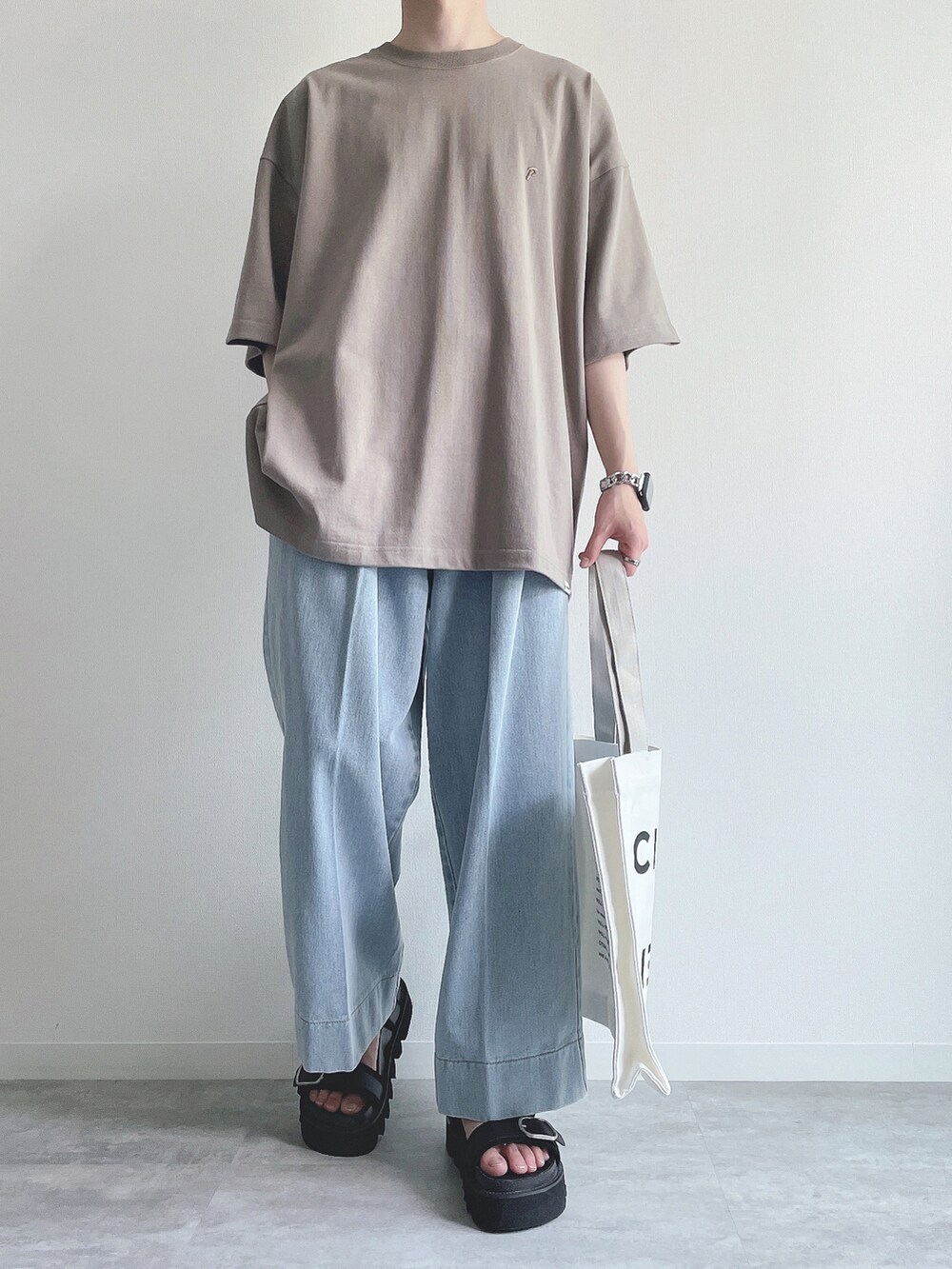 ベージュ系のTシャツ/カットソー、ブルー系のデニムパンツ、ブラック系のサンダルを着用したメンズの夏コーディネートの2枚目の写真