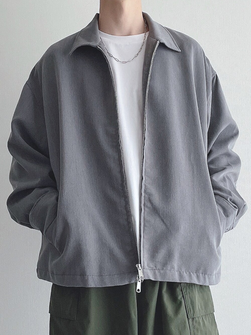 グレー系のブルゾン、ホワイト系のTシャツ/カットソー、グリーン系のカーゴパンツを着用したメンズの秋コーディネートの4枚目の写真