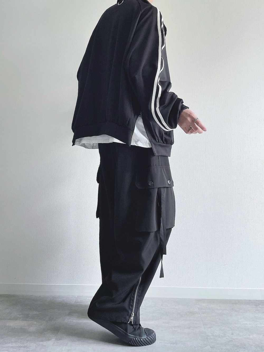 ブラック系のブルゾン、ホワイト系のTシャツ/カットソー、ブラック系のカーゴパンツを着用したメンズの春コーディネートの4枚目の写真