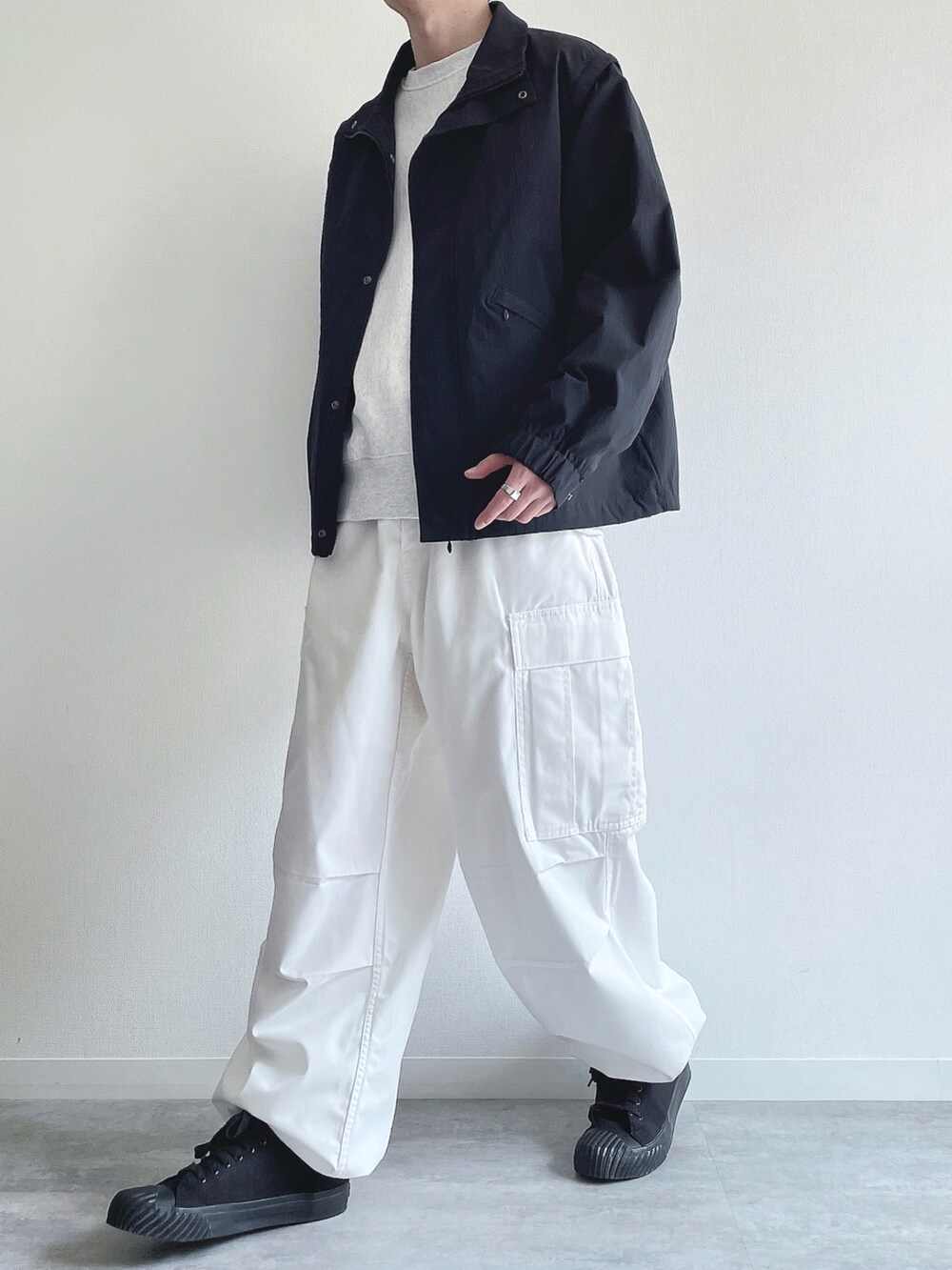 ブラック系のブルゾン、グレー系のトップス、ホワイト系のパンツを着用したメンズの春コーディネートの5枚目の写真