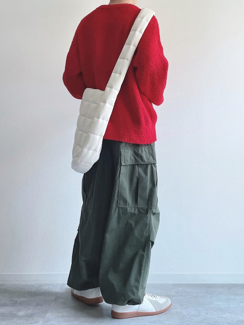 レッド系のニット/セーター、グリーン系のカーゴパンツ、ホワイト系のスニーカーを着用したメンズの冬コーディネートの4枚目の写真