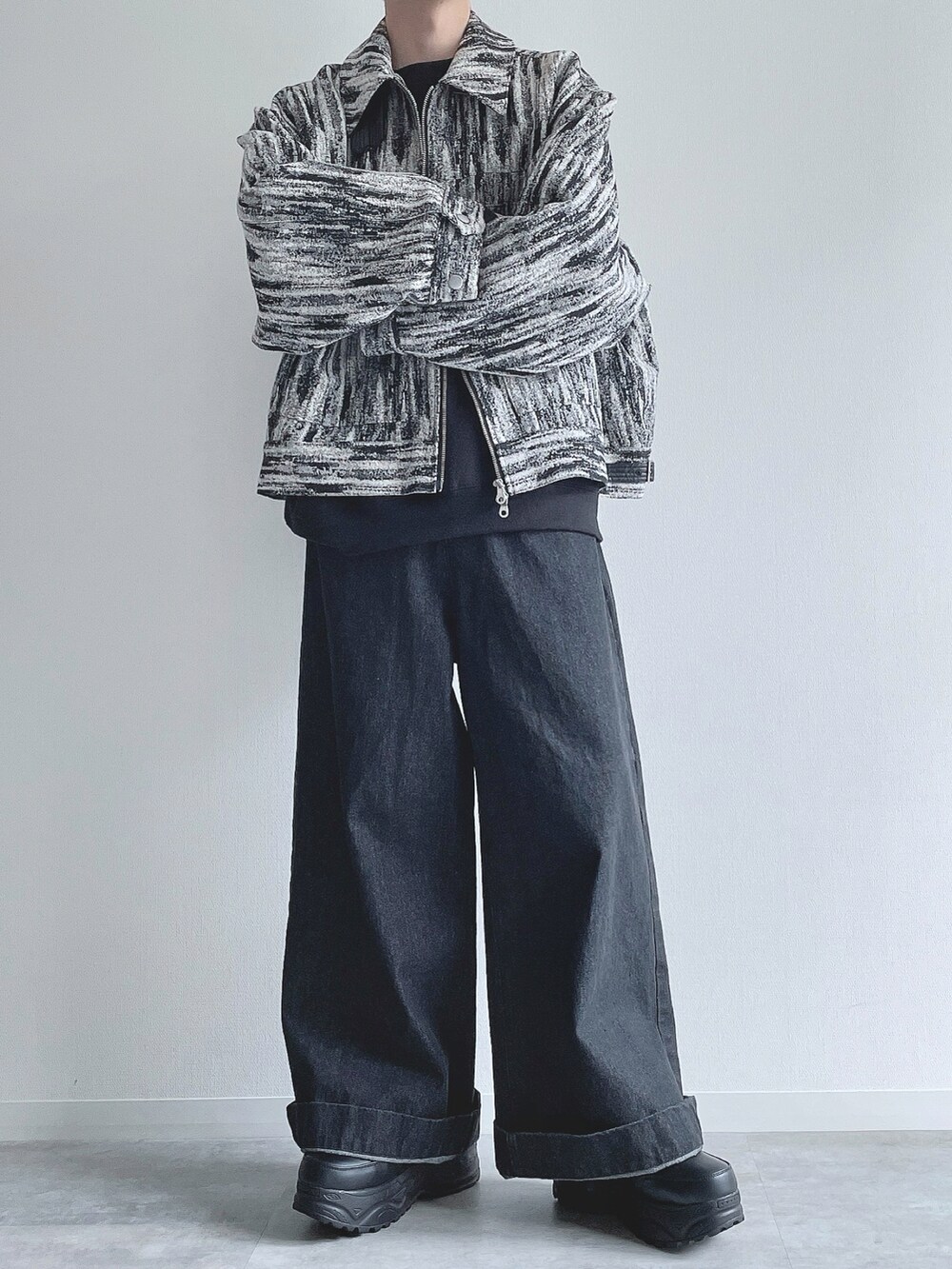 ホワイト系のブルゾン、ブラック系のトップス、ブラック系のデニムパンツを着用したメンズの冬コーディネートの4枚目の写真