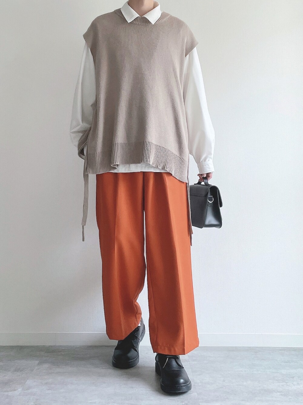 ベージュ系のベスト、ホワイト系のシャツ/ブラウス、オレンジ系のスラックスを着用したメンズの冬コーディネートの2枚目の写真