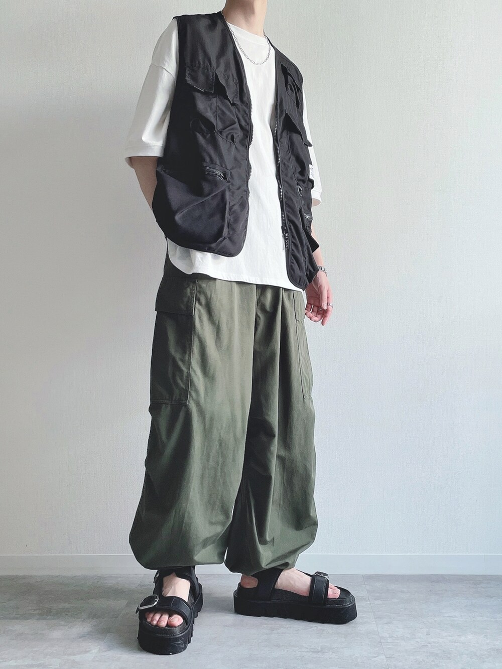 ブラック系のベスト、ホワイト系のTシャツ/カットソー、グリーン系のカーゴパンツを着用したメンズの夏コーディネートの2枚目の写真