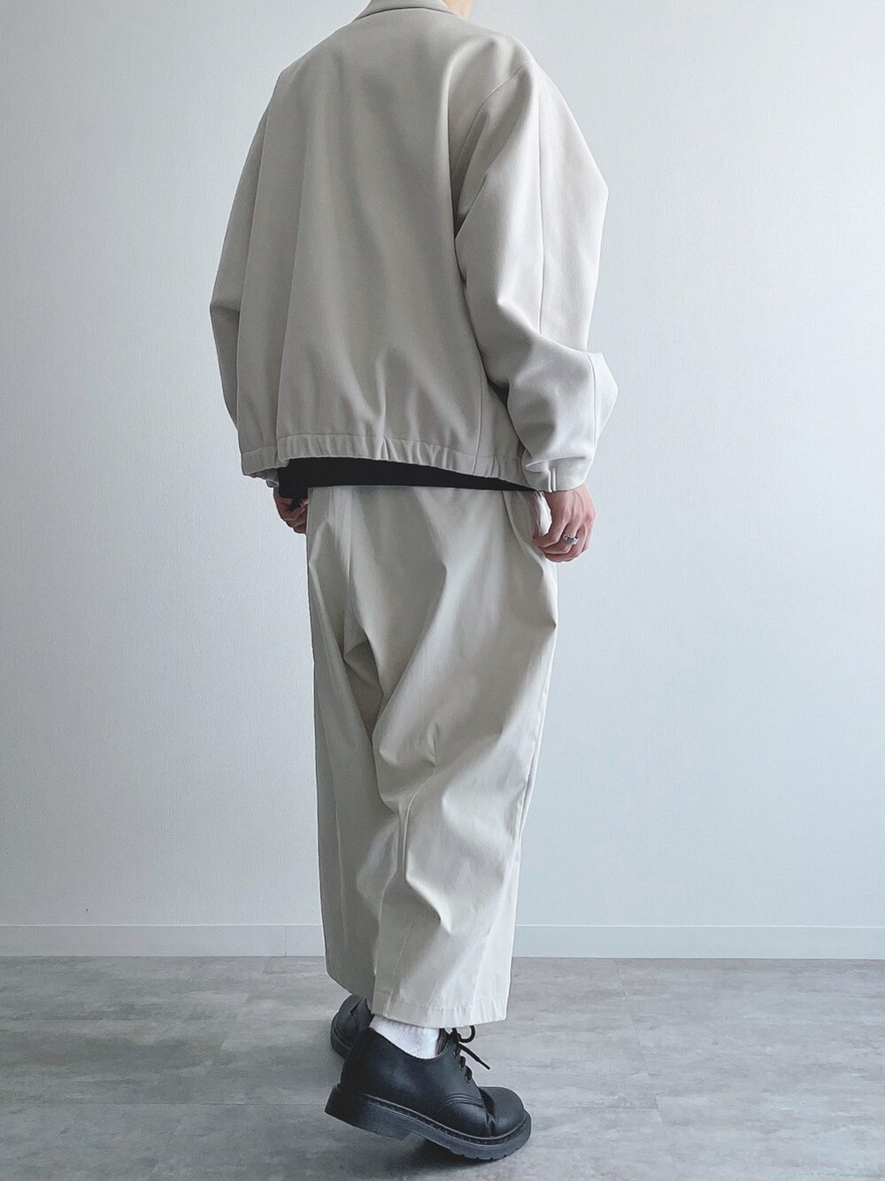 ホワイト系のブルゾン、ブラック系のトップス、ホワイト系のその他パンツを着用したメンズの秋コーディネートの3枚目の写真