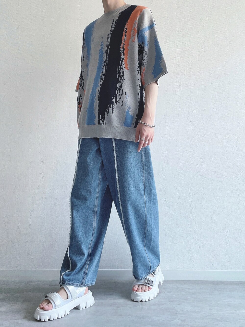 グレー系のニット/セーター、ブルー系のデニムパンツ、ホワイト系のサンダルを着用したメンズの夏コーディネートの5枚目の写真