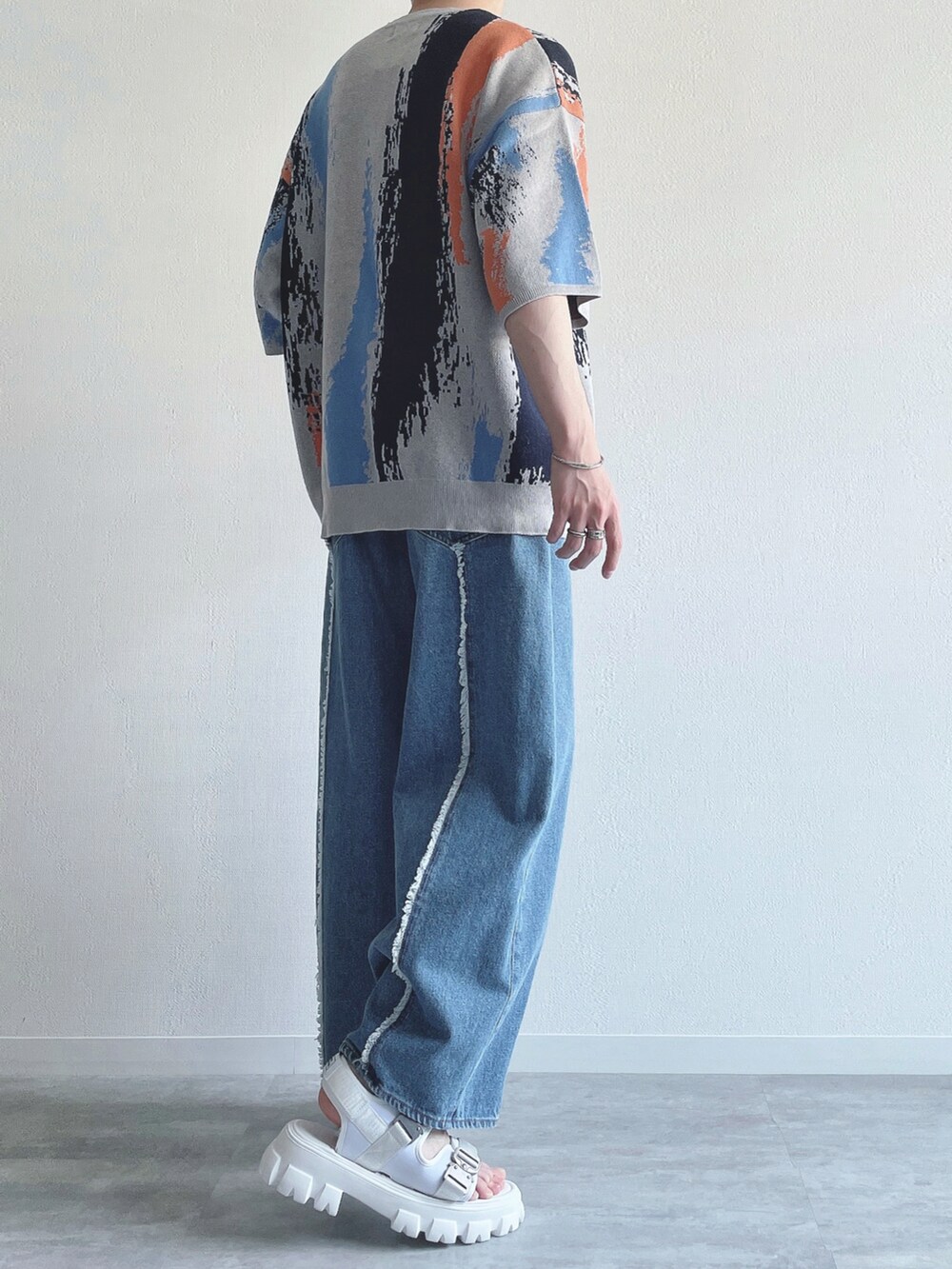 グレー系のニット/セーター、ブルー系のデニムパンツ、ホワイト系のサンダルを着用したメンズの夏コーディネートの4枚目の写真