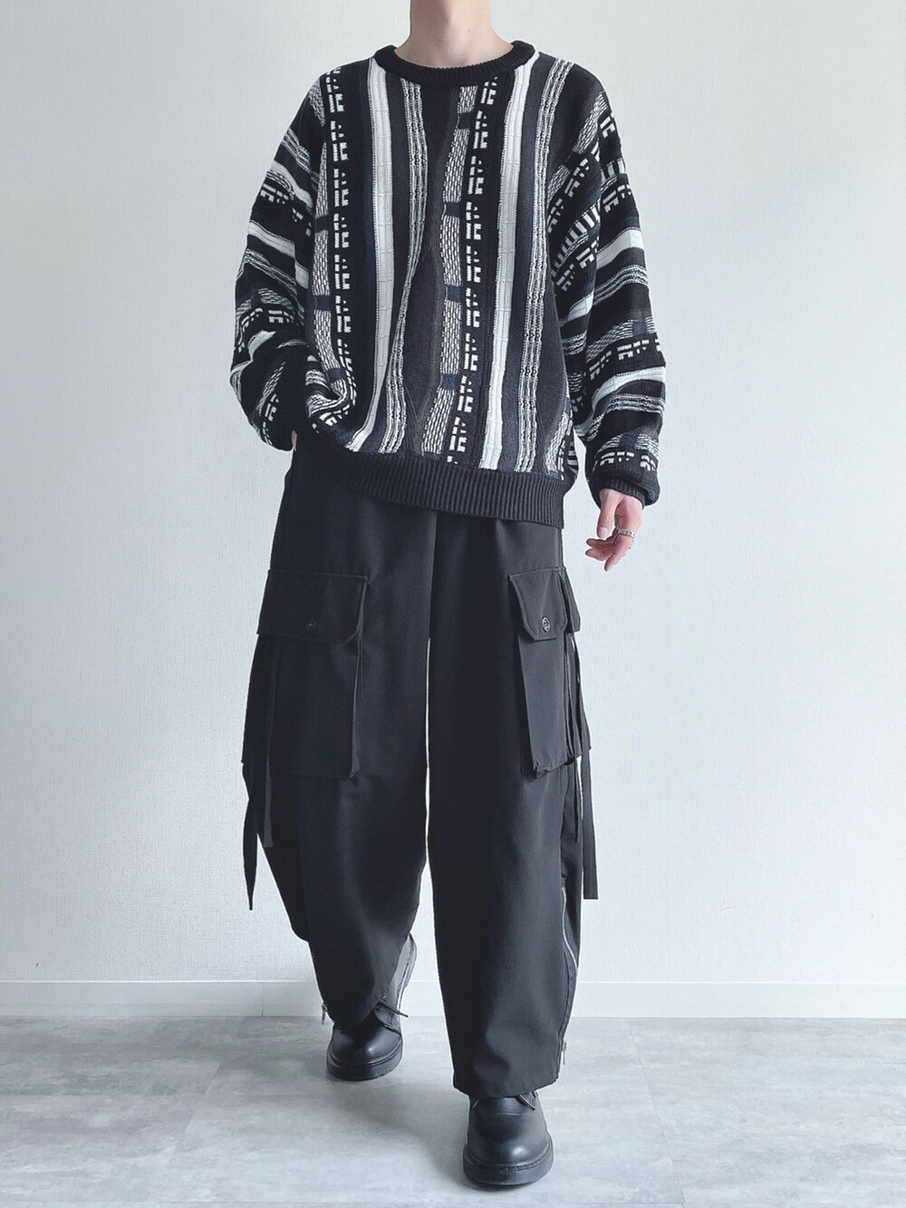 ブラック系のニット/セーター、ブラック系のカーゴパンツ、ブラック系のスニーカーを着用したメンズの秋コーディネートの2枚目の写真