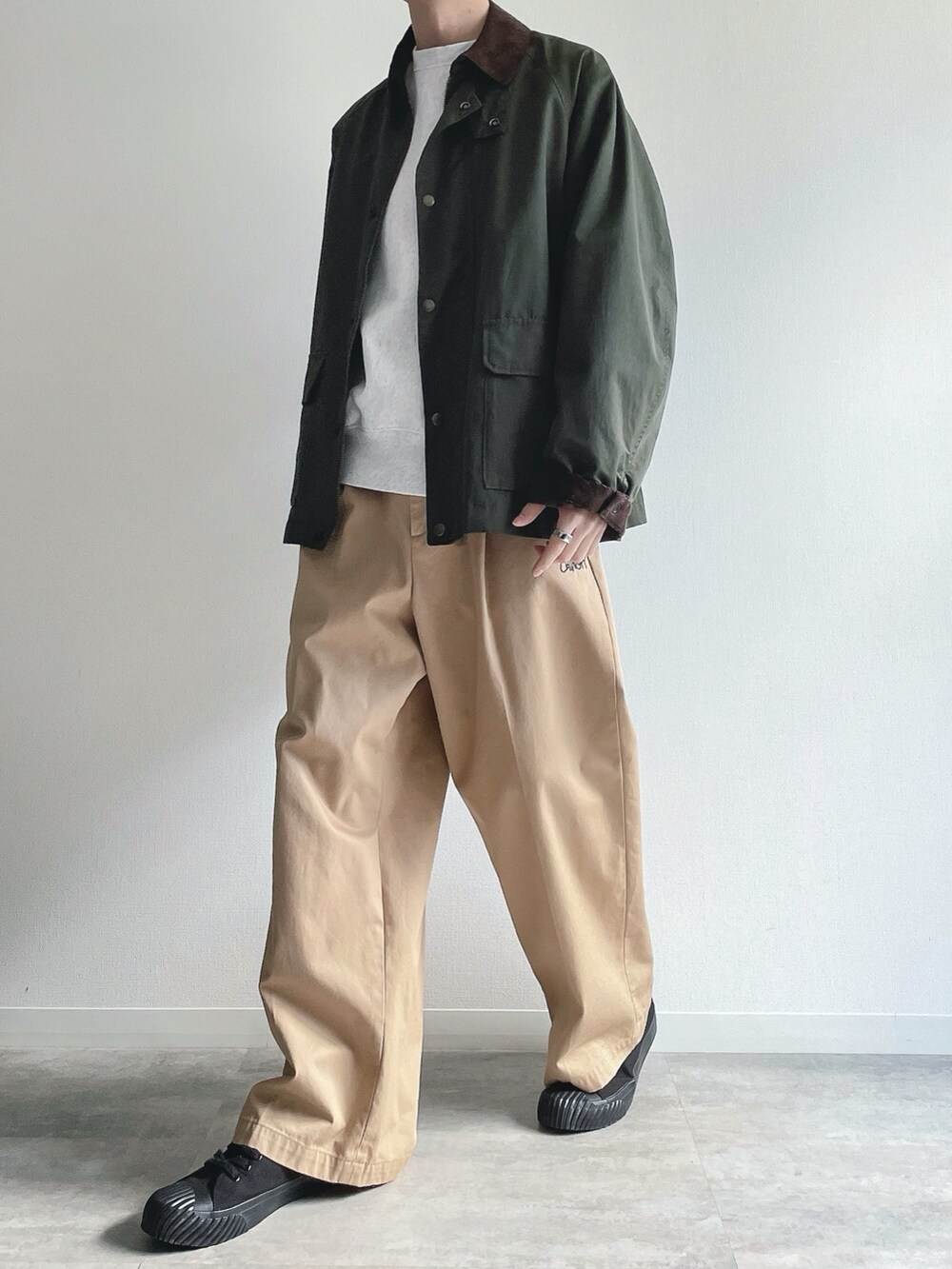 グリーン系のミリタリージャケット、グレー系のトップス、ベージュ系のチノパンツを着用したメンズの冬コーディネートの5枚目の写真