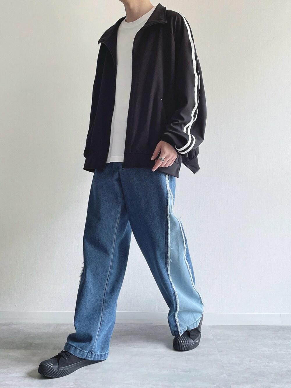 ブラック系のブルゾン、ホワイト系のTシャツ/カットソー、ブルー系のデニムパンツを着用したメンズの秋コーディネートの5枚目の写真