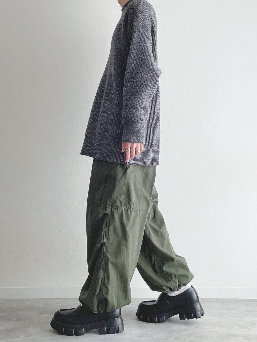 グレー系のニット/セーター、グリーン系のカーゴパンツ、ブラック系のローファーを着用したメンズの秋コーディネートの2枚目の写真