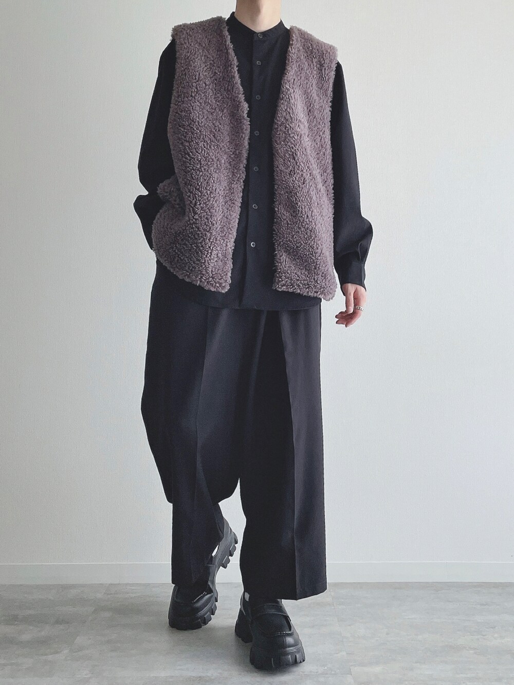 グレー系のベスト、ブラック系のトップス、ブラック系のスラックスを着用したメンズの秋コーディネートの5枚目の写真