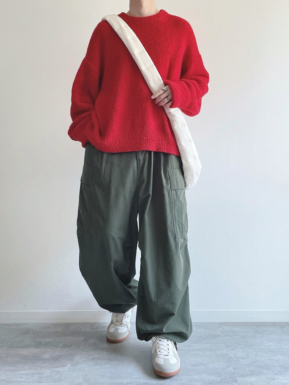 レッド系のニット/セーター、グリーン系のカーゴパンツ、ホワイト系のスニーカーを着用したメンズの冬コーディネートの2枚目の写真