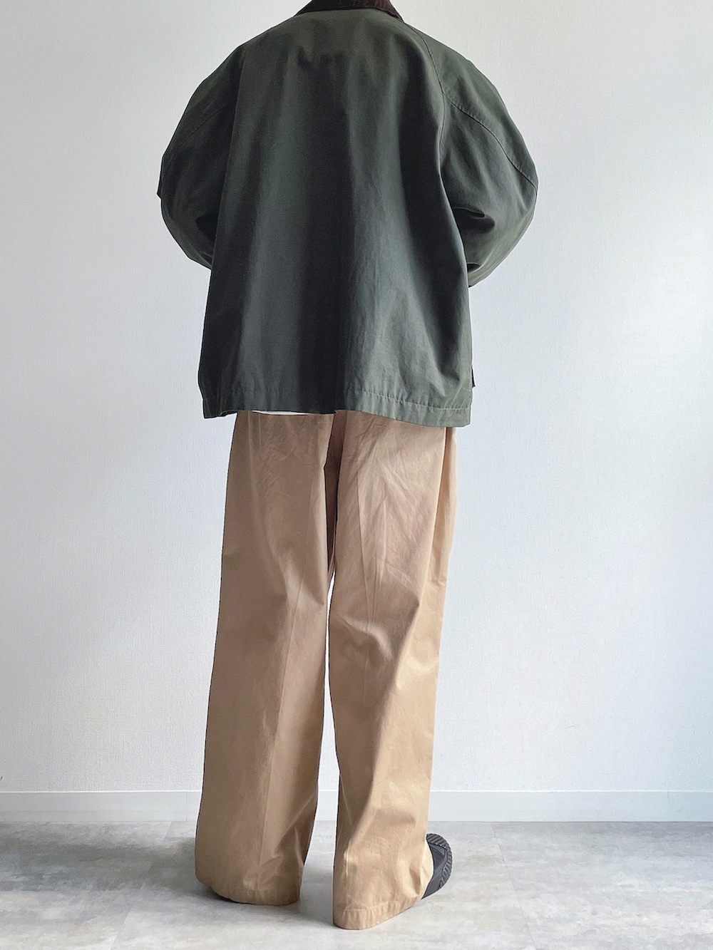 グリーン系のミリタリージャケット、グレー系のトップス、ベージュ系のチノパンツを着用したメンズの冬コーディネートの4枚目の写真