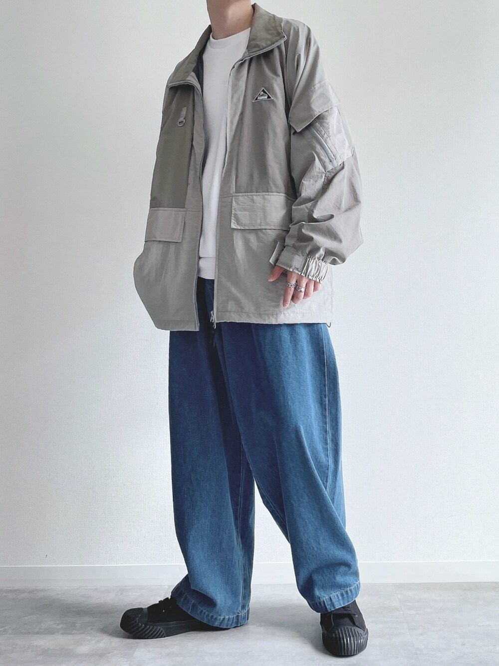 グレー系のブルゾン、ホワイト系のトップス、ブルー系のデニムパンツを着用したメンズの冬コーディネートの4枚目の写真