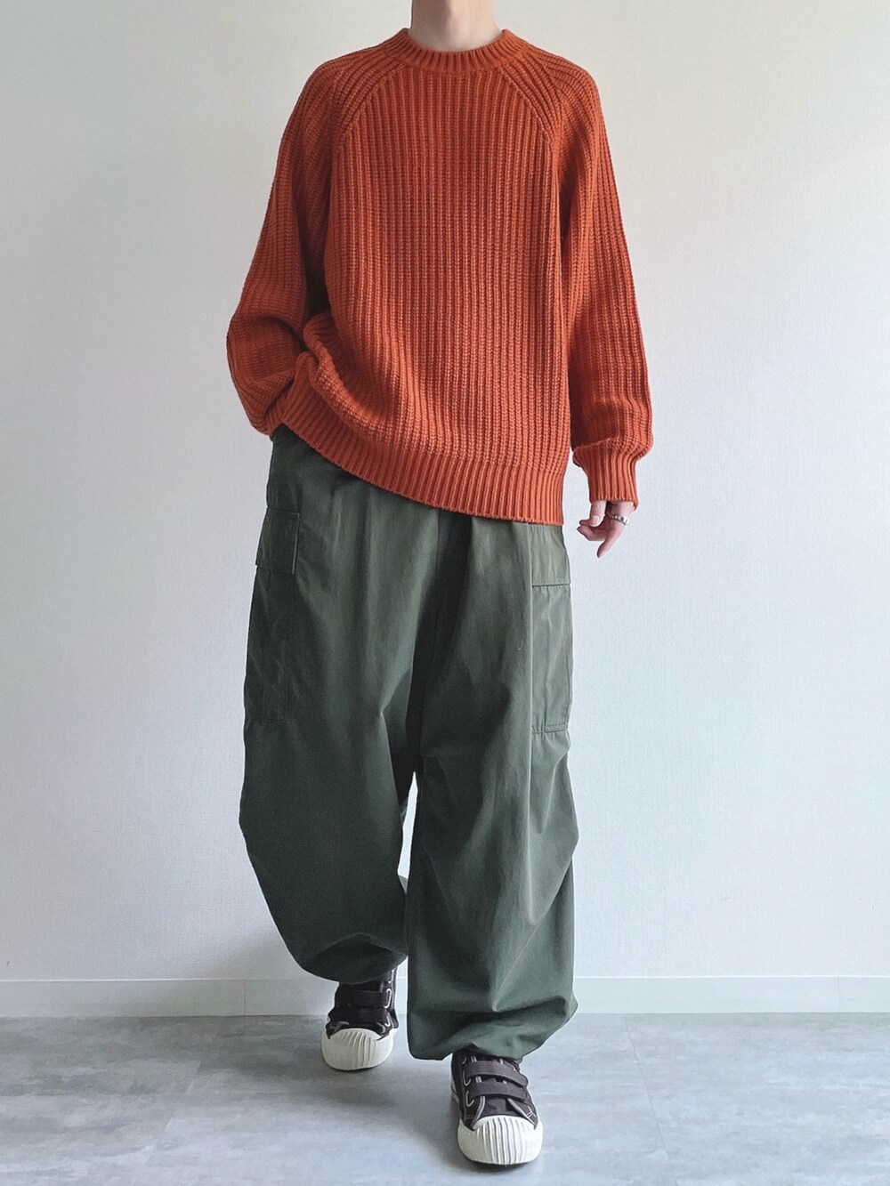 オレンジ系のトップス、グリーン系のカーゴパンツ、ブラウン系のスニーカーを着用したメンズの冬コーディネートの2枚目の写真