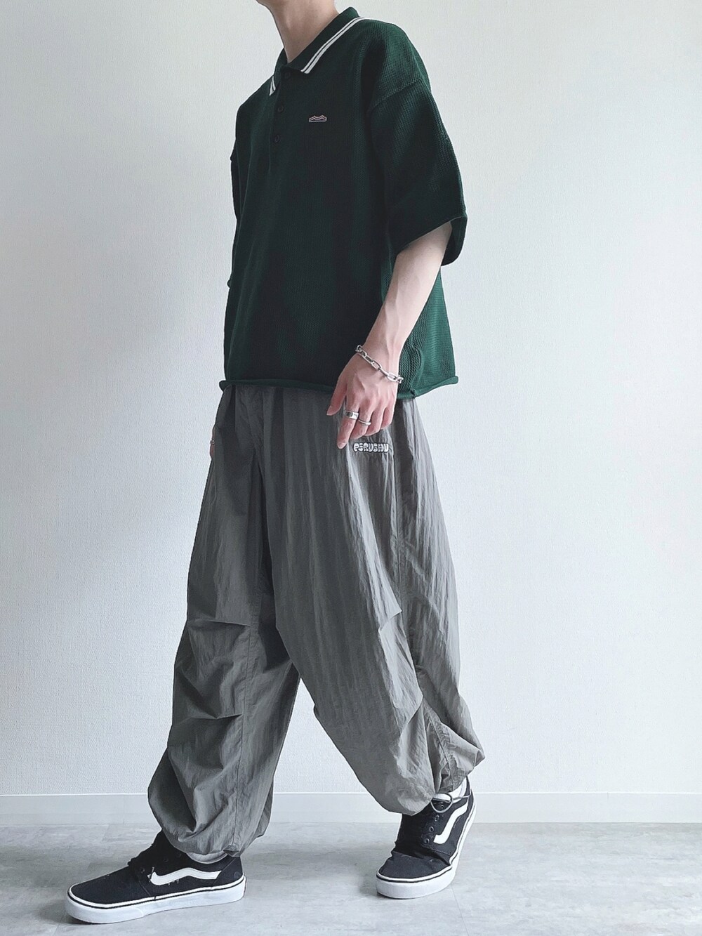 グリーン系のポロシャツ、グレー系のその他パンツ、ブラック系のスニーカーを着用したメンズの夏コーディネートの5枚目の写真