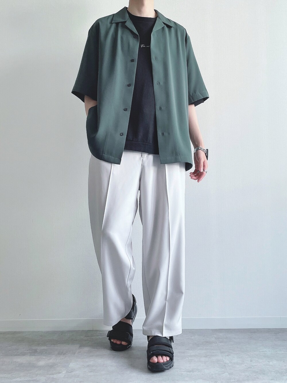 グリーン系のトップス、ブラック系のTシャツ/カットソー、ホワイト系のスラックスを着用したメンズの夏コーディネートの2枚目の写真