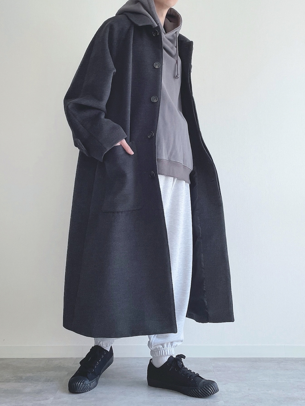 グレー系のステンカラーコート、ブルー系のTシャツ/カットソー、グレー系のスウェットパンツを着用したメンズの冬コーディネートの4枚目の写真